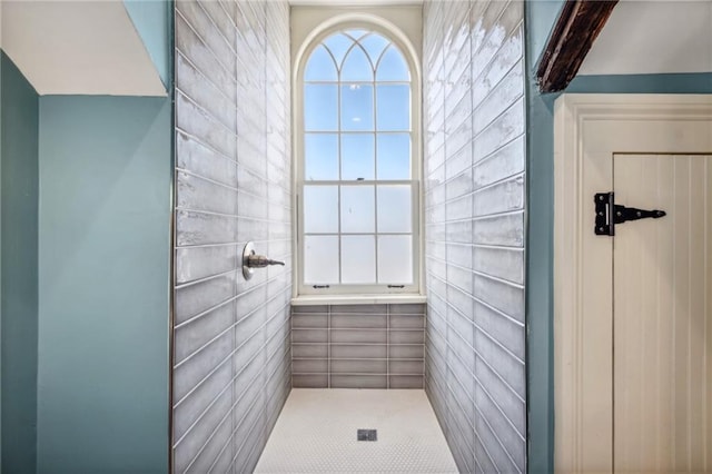 bathroom featuring walk in shower and tile walls