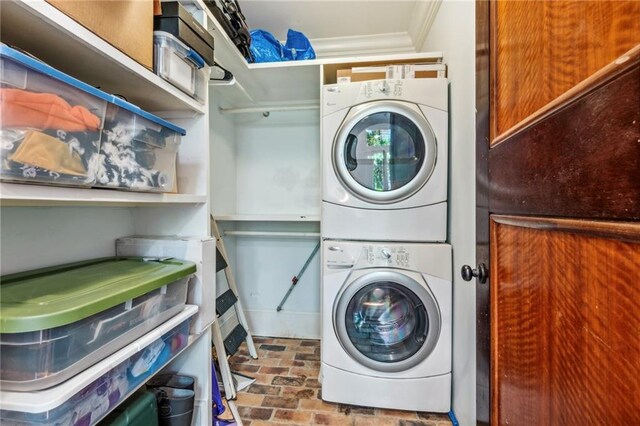 washroom with stacked washer / drying machine and crown molding