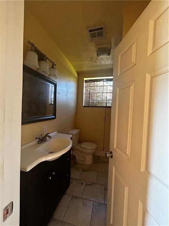 bathroom featuring tile patterned flooring, a textured ceiling, vanity, and toilet