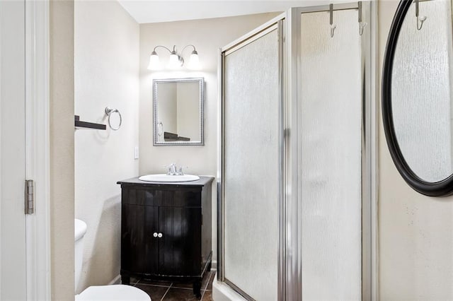 bathroom featuring toilet, vanity, tile patterned floors, and a shower with door