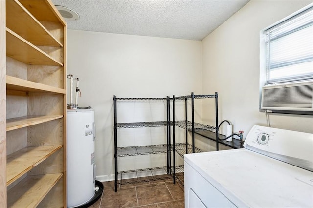 washroom with a textured ceiling, electric water heater, washer / clothes dryer, and dark tile patterned floors