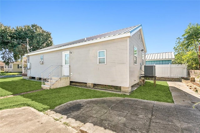 rear view of property featuring central AC unit and a lawn