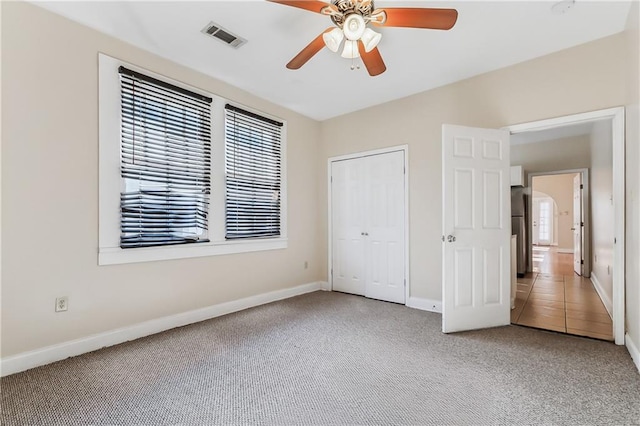 unfurnished bedroom featuring carpet flooring, multiple windows, ceiling fan, and a closet