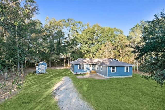 single story home featuring a front yard and a storage shed