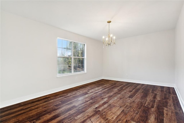 empty room with a chandelier and dark hardwood / wood-style flooring