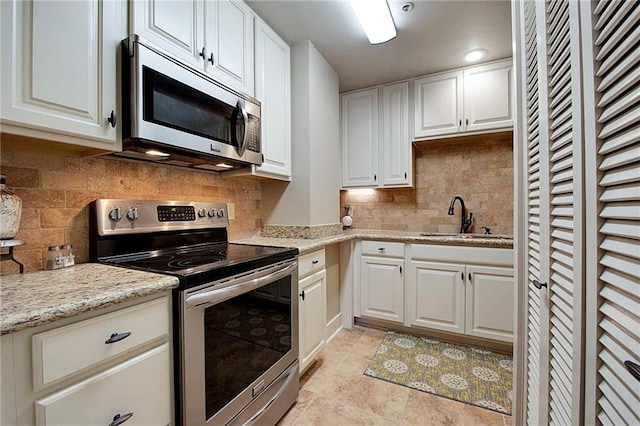 kitchen with decorative backsplash, white cabinetry, sink, and stainless steel appliances