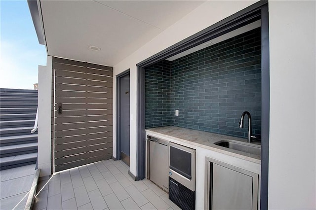 interior space with decorative backsplash, stainless steel refrigerator, and sink