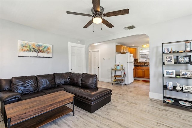 living room with ceiling fan, sink, and light hardwood / wood-style floors