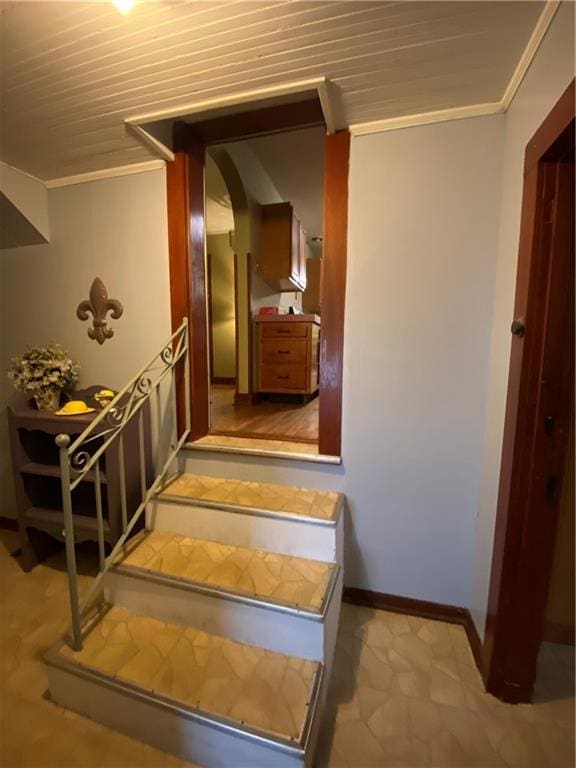 staircase featuring wood ceiling and ornamental molding