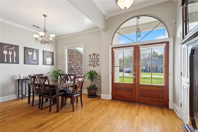 dining area featuring crown molding, french doors, light hardwood / wood-style floors, and an inviting chandelier