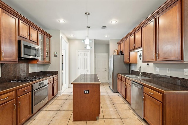 kitchen with sink, a center island, light tile patterned floors, and appliances with stainless steel finishes