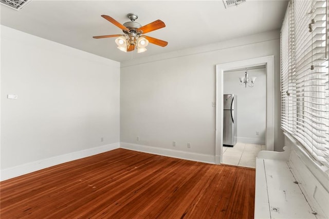 unfurnished bedroom with stainless steel fridge, a closet, light hardwood / wood-style floors, and ceiling fan with notable chandelier