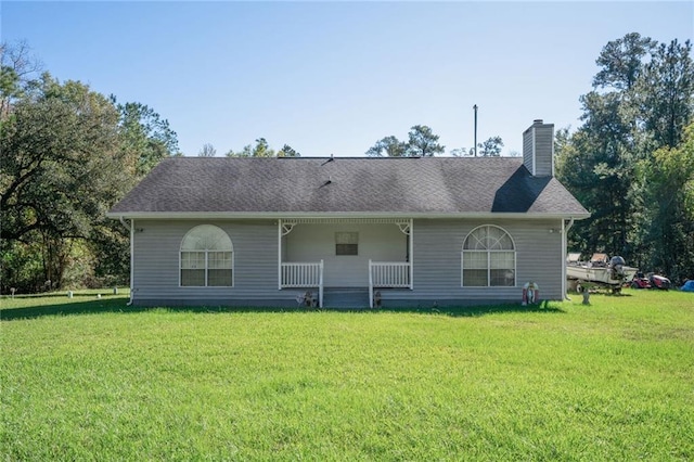 rear view of house with a lawn and a porch