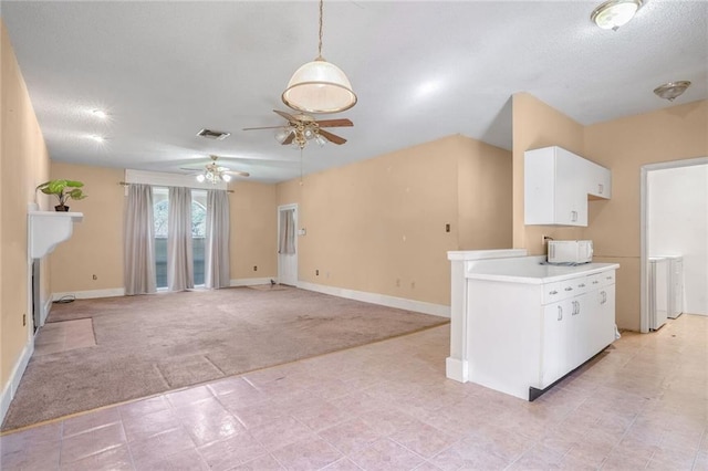 kitchen featuring pendant lighting, light carpet, white cabinets, ceiling fan, and a textured ceiling