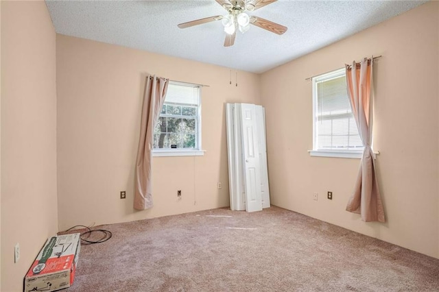 carpeted spare room with ceiling fan and a textured ceiling