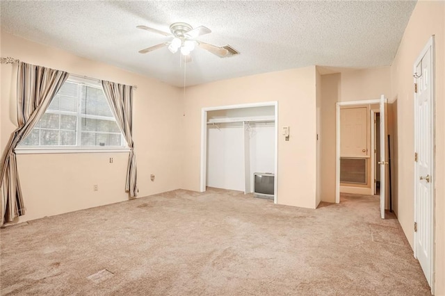 unfurnished bedroom with light carpet, a textured ceiling, and ceiling fan