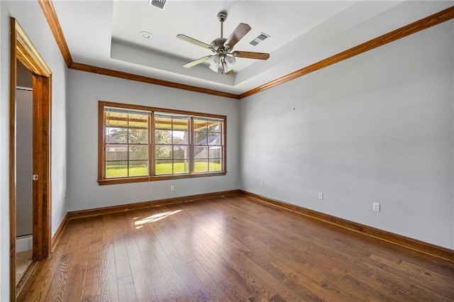 spare room featuring ornamental molding, a raised ceiling, ceiling fan, and dark wood-type flooring