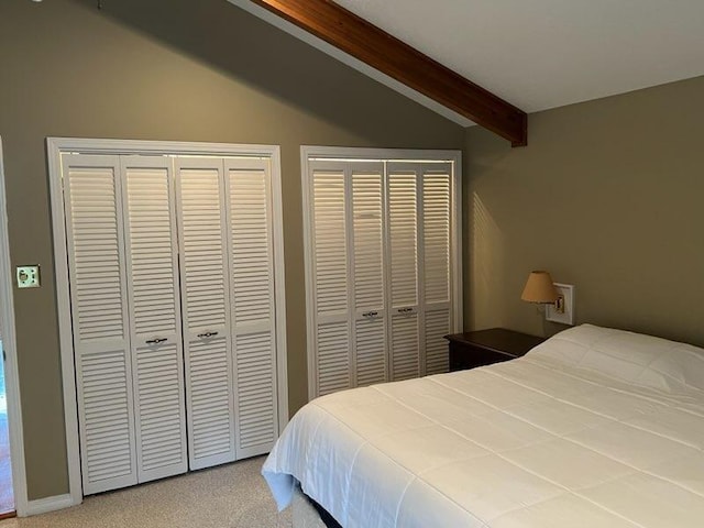 carpeted bedroom with multiple closets and vaulted ceiling with beams