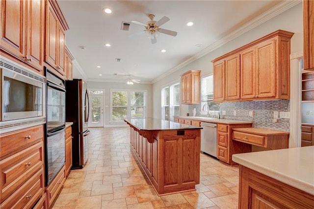 kitchen featuring tasteful backsplash, stainless steel appliances, ceiling fan, crown molding, and a center island