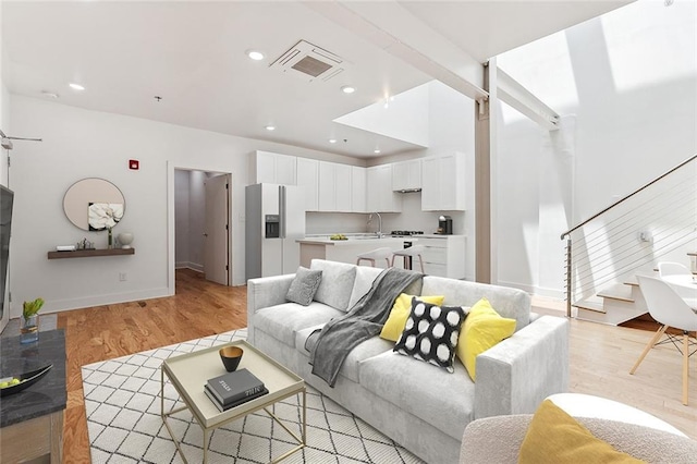 living area with light wood-type flooring, visible vents, recessed lighting, stairway, and baseboards