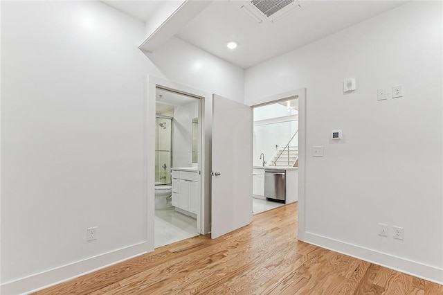 interior space with visible vents, light wood-style flooring, baseboards, and a sink