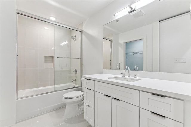 full bath featuring tile patterned floors, toilet, vanity, and shower / bath combination with glass door