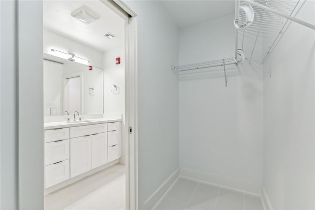 walk in closet with light tile patterned floors, visible vents, and a sink