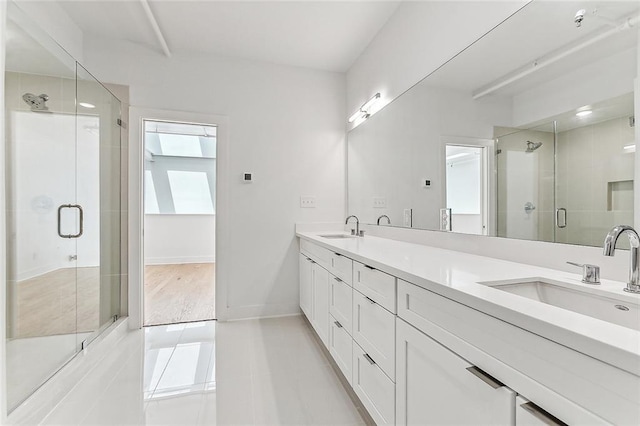 bathroom featuring double vanity, a stall shower, baseboards, and a sink