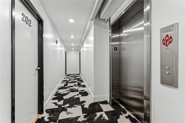 corridor featuring tile patterned floors, elevator, recessed lighting, and baseboards