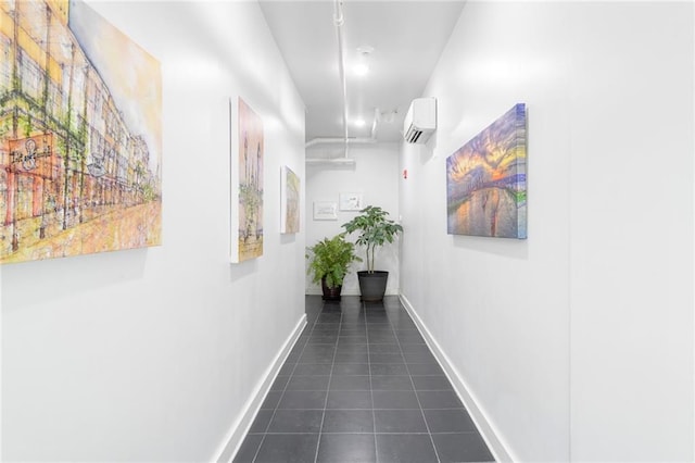 hall with a wall mounted air conditioner, baseboards, and dark tile patterned flooring