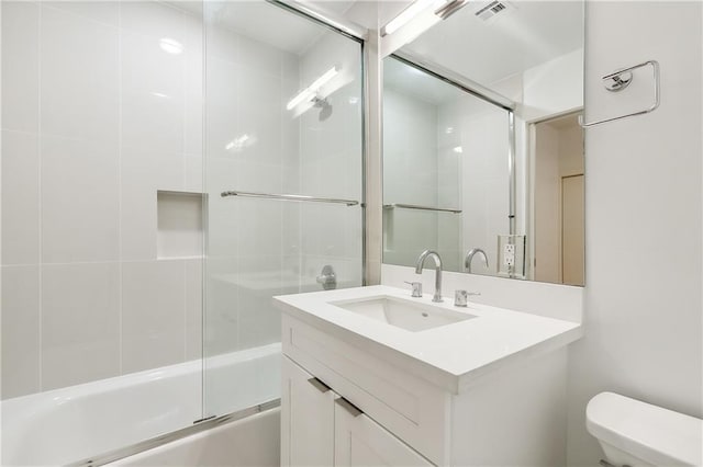 full bathroom featuring enclosed tub / shower combo, vanity, and toilet