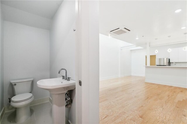 bathroom featuring wood-type flooring, toilet, and sink