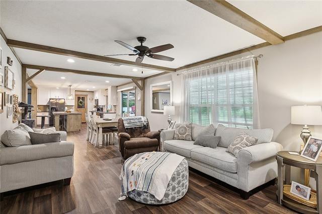 living room with dark hardwood / wood-style floors, ceiling fan, and beam ceiling