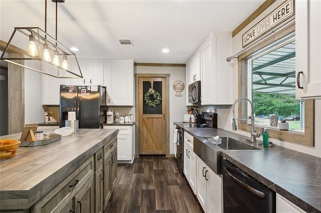 kitchen with sink, dark wood-type flooring, hanging light fixtures, white cabinets, and black appliances