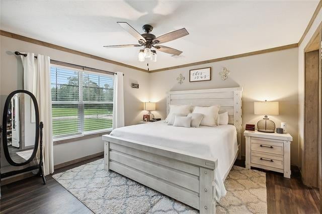 bedroom with ornamental molding, ceiling fan, and dark wood-type flooring