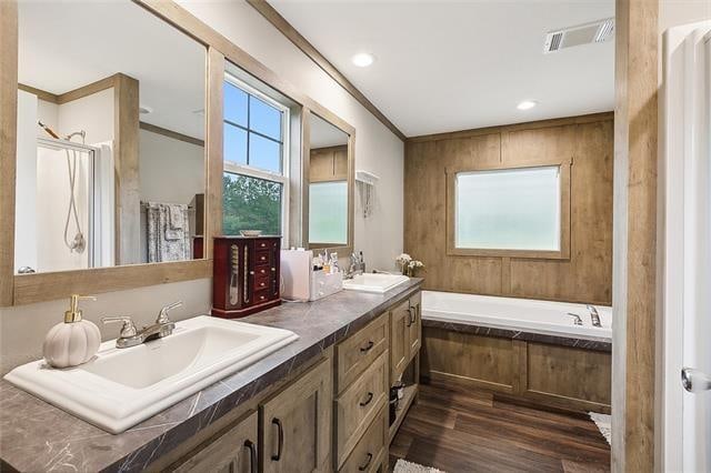 bathroom featuring tiled tub, vanity, ornamental molding, and hardwood / wood-style flooring