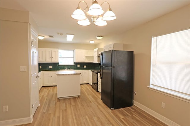 kitchen with light wood-type flooring, black appliances, decorative light fixtures, white cabinets, and a kitchen island