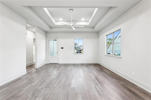 spare room featuring a raised ceiling, light hardwood / wood-style flooring, and ceiling fan