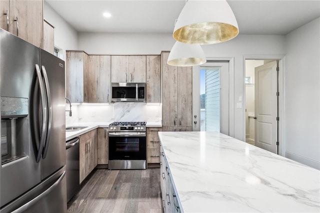 kitchen with pendant lighting, sink, light stone counters, dark hardwood / wood-style flooring, and stainless steel appliances