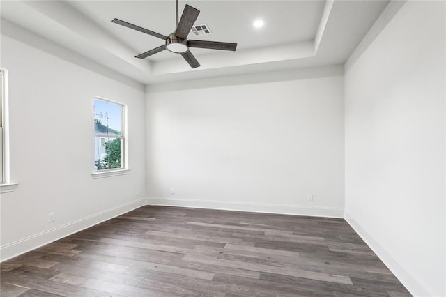 unfurnished room featuring dark hardwood / wood-style floors, a raised ceiling, and ceiling fan