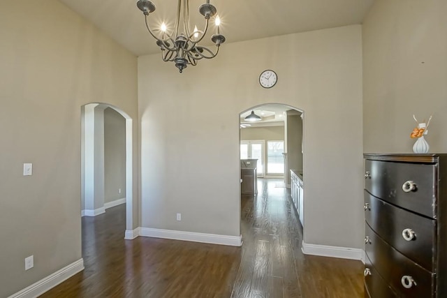 unfurnished dining area featuring ceiling fan with notable chandelier and dark hardwood / wood-style flooring