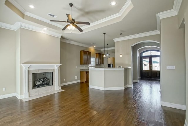 unfurnished living room featuring french doors, crown molding, dark hardwood / wood-style floors, ceiling fan, and a fireplace