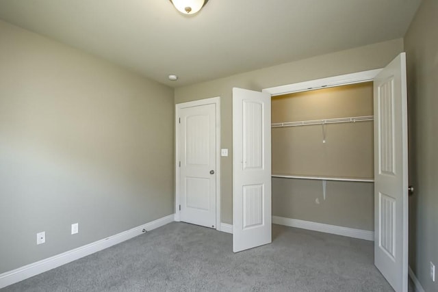 unfurnished bedroom featuring light colored carpet and a closet