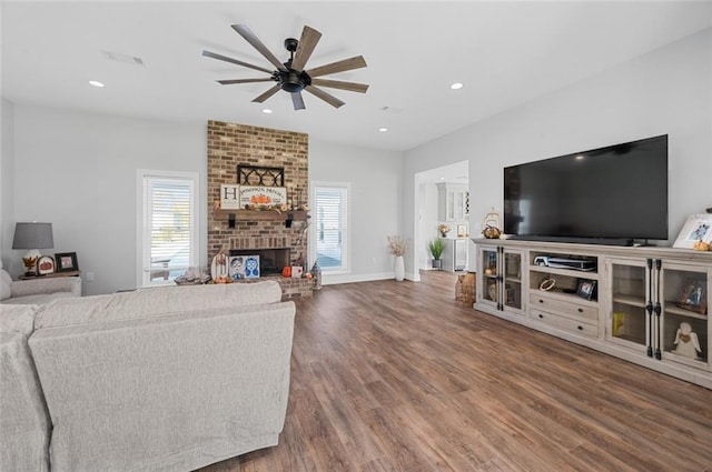 living room featuring a fireplace, dark hardwood / wood-style flooring, plenty of natural light, and ceiling fan