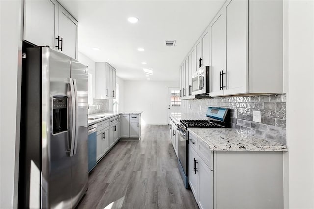 1917 Generes Dr, Harahan, LA 70123 - kitchen with stainless steel appliances, light wood finished floors, recessed lighting, decorative backsplash, and light stone countertops