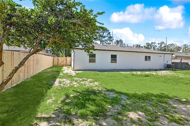 back of property with central AC unit and a yard