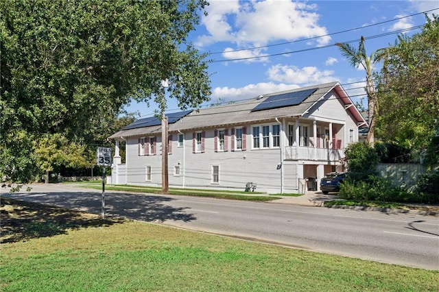 view of front of property featuring a front yard and solar panels