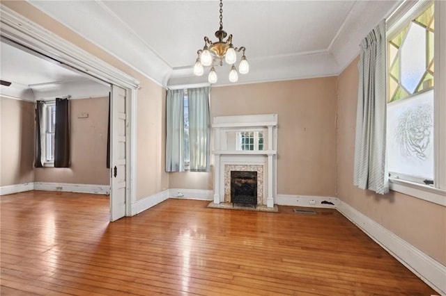 unfurnished living room with a premium fireplace, an inviting chandelier, ornamental molding, and light wood-type flooring