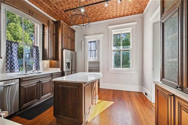 kitchen featuring ornamental molding, stainless steel appliances, sink, hardwood / wood-style floors, and a kitchen island