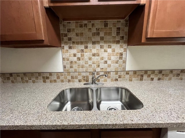 details with decorative backsplash, light stone countertops, and sink